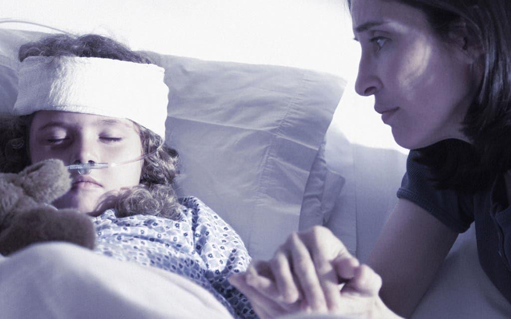 A child asleep in the hospital and her mother holding the hand.