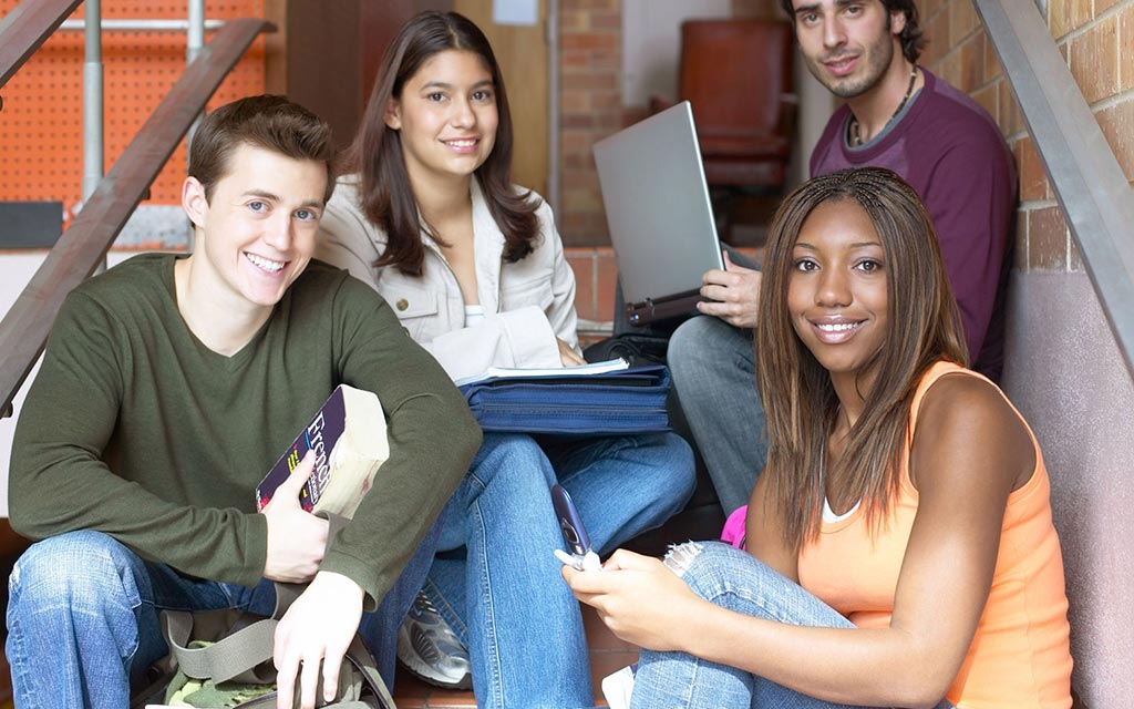 A group of students sitting on stairs outside a building.