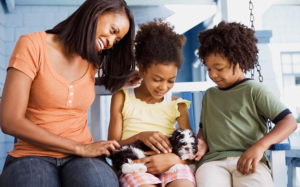 A mother and her children holding a puppy.