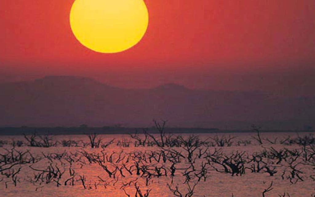 The sun sets over the flooded river.