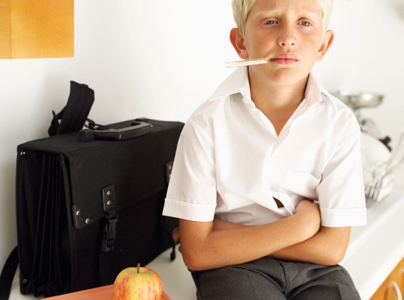 Boy sitting in a school clinic getting his temperature checked.