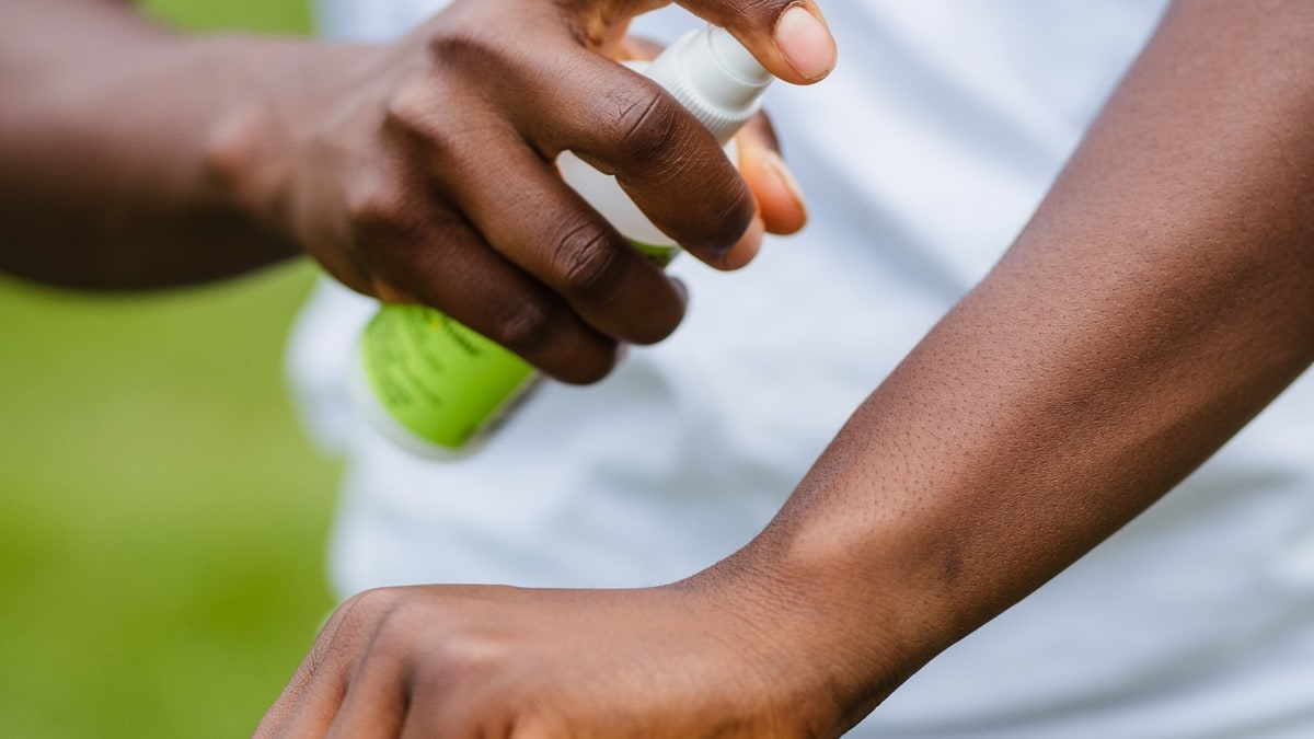 Persona aplicándose repelente de insectos en el brazo