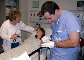 Patient in a hospital bed being attended to by a doctor and nurse