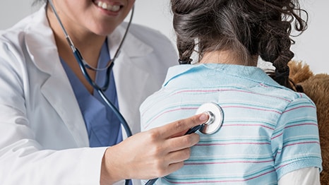 A healthcare provider listens to the lungs of a young girl.