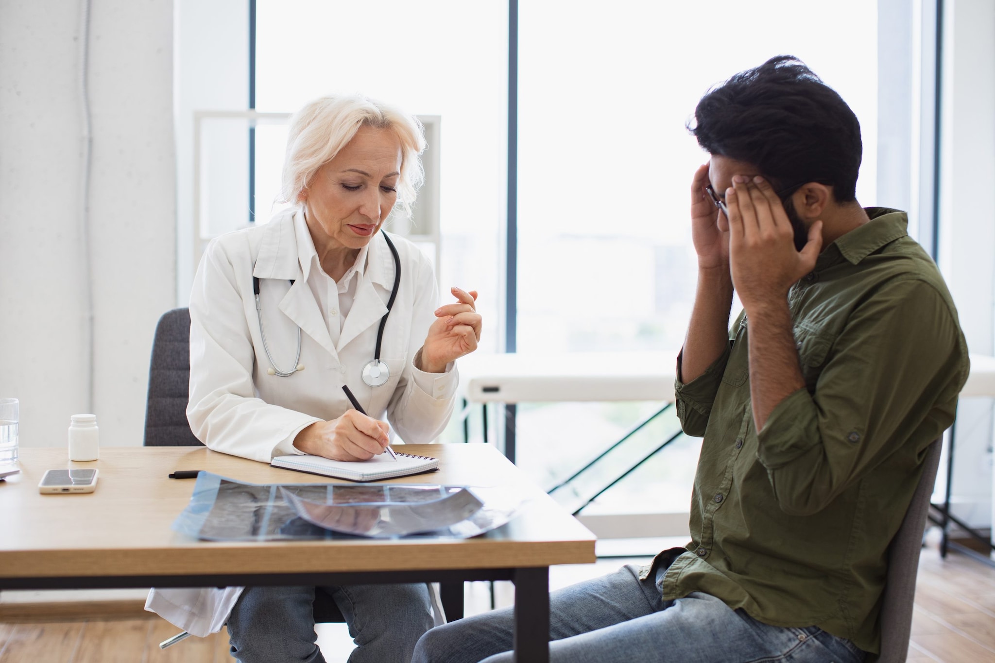 Man holds his head while talking with a healthcare provider