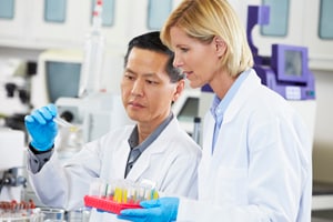 Two scientists in lab, observing a sample together