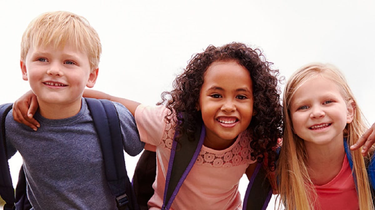 A group of school age children wearing backpacks