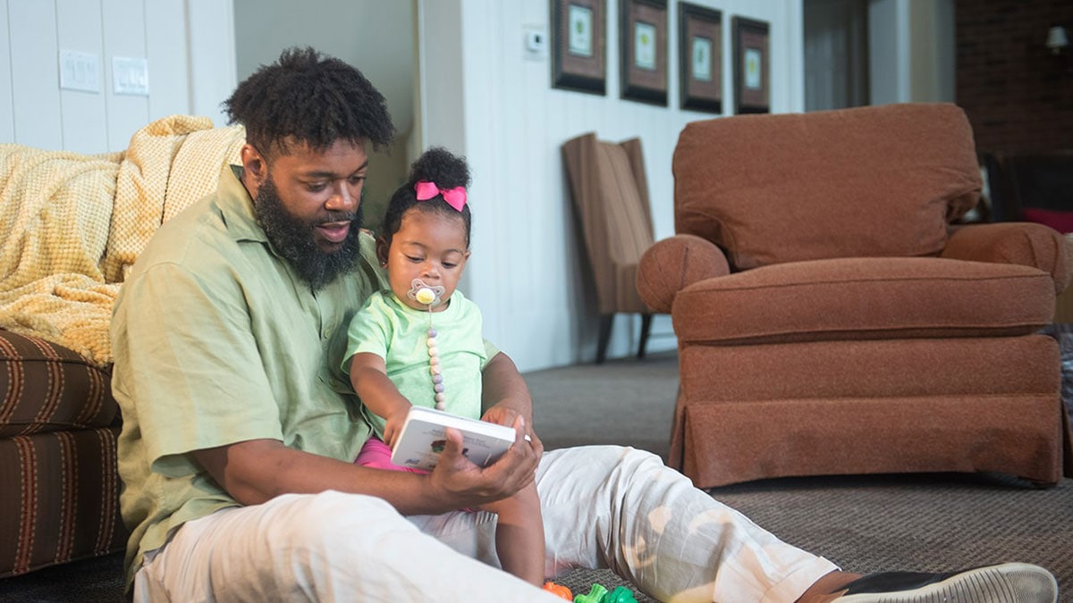 A dad reading to his daughter.