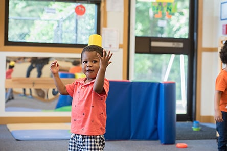 30 month year old baby standing with toy on head