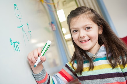 5 year old girl drawing on a board