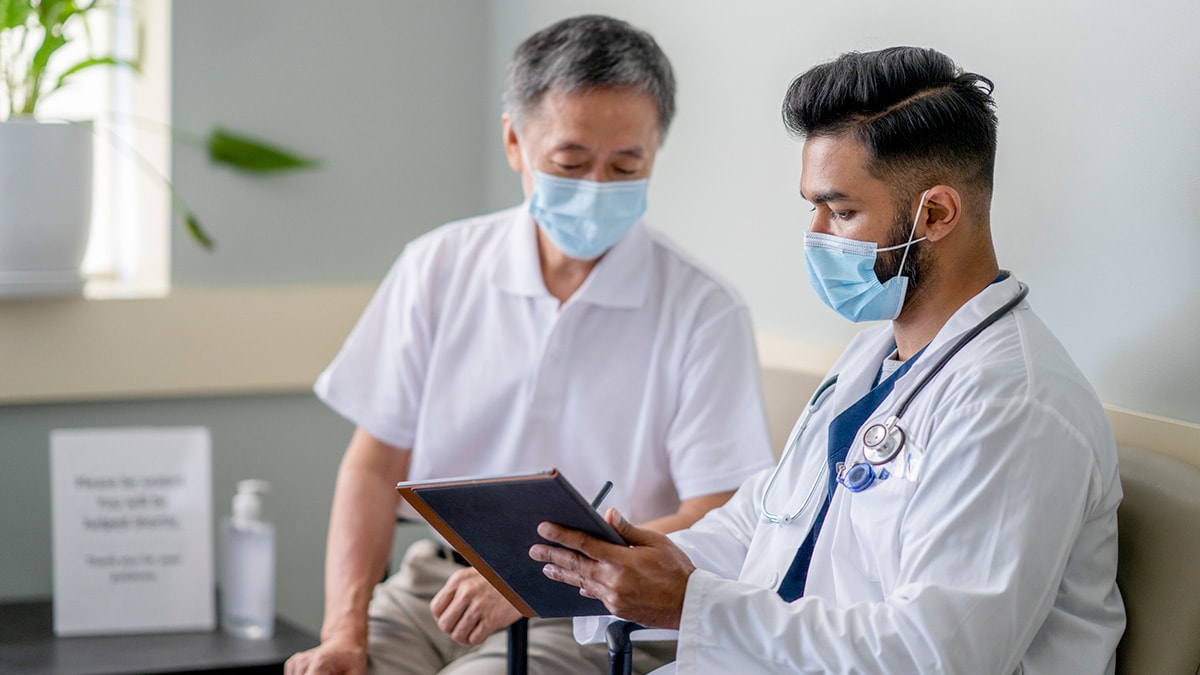 Patient and doctor wearing masks going over medical chart