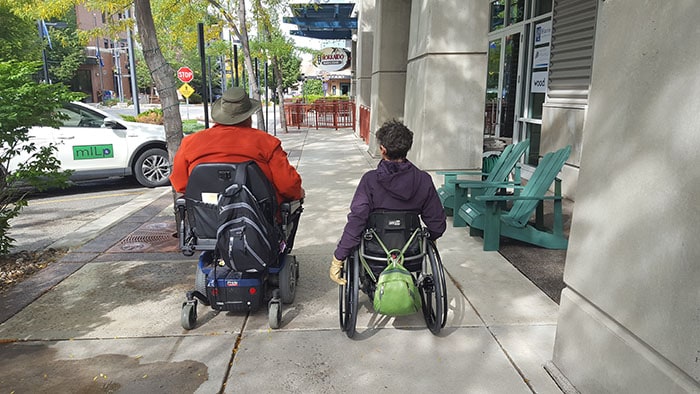 Man on scooter with woman in wheelchair