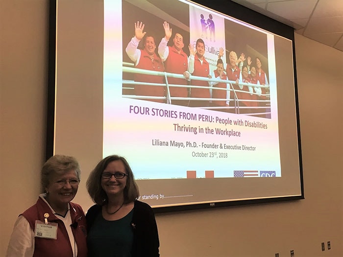 Liliana Mayo and Georgina Peacock stand together in front of the presentation about CASP