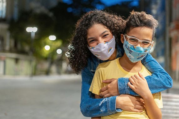 Mom hugging son. Both wearing face masks.