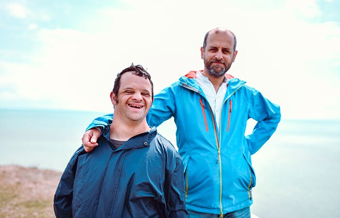 A man with a disability and a friend on the beach