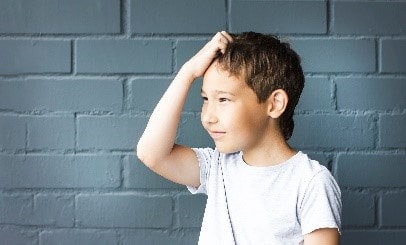 A child holding his hand to his head