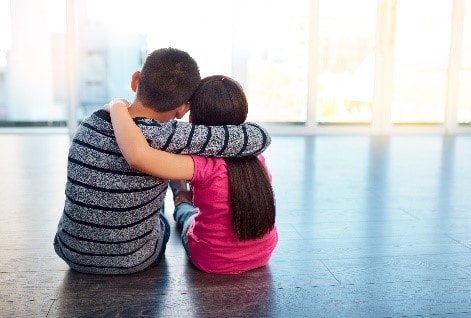 Children sitting together with their arms around each other