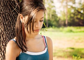 young girl in front of a tree