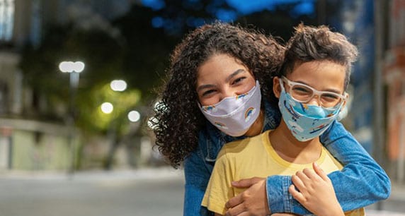 Mom hugging son. Both wearing face masks.