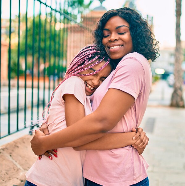 A mother hugs her teenaged daughter.