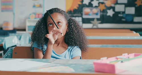 Girl balances a pencil between her fingers as she appears distracted while studying.