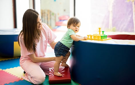 An early education provider plays with two children.