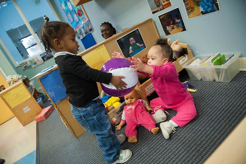 two girls play with a ball