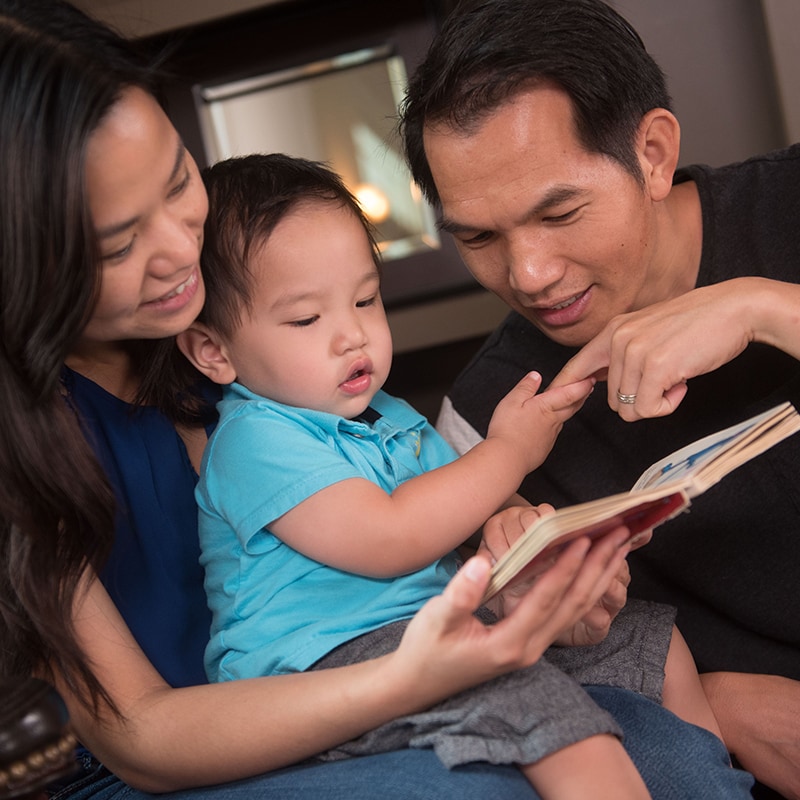 Niño mirando un libro con sus padres