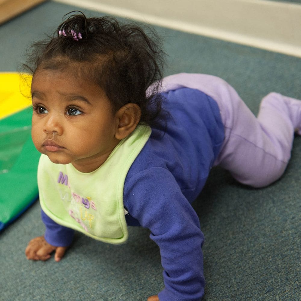 A baby crawls across the floor