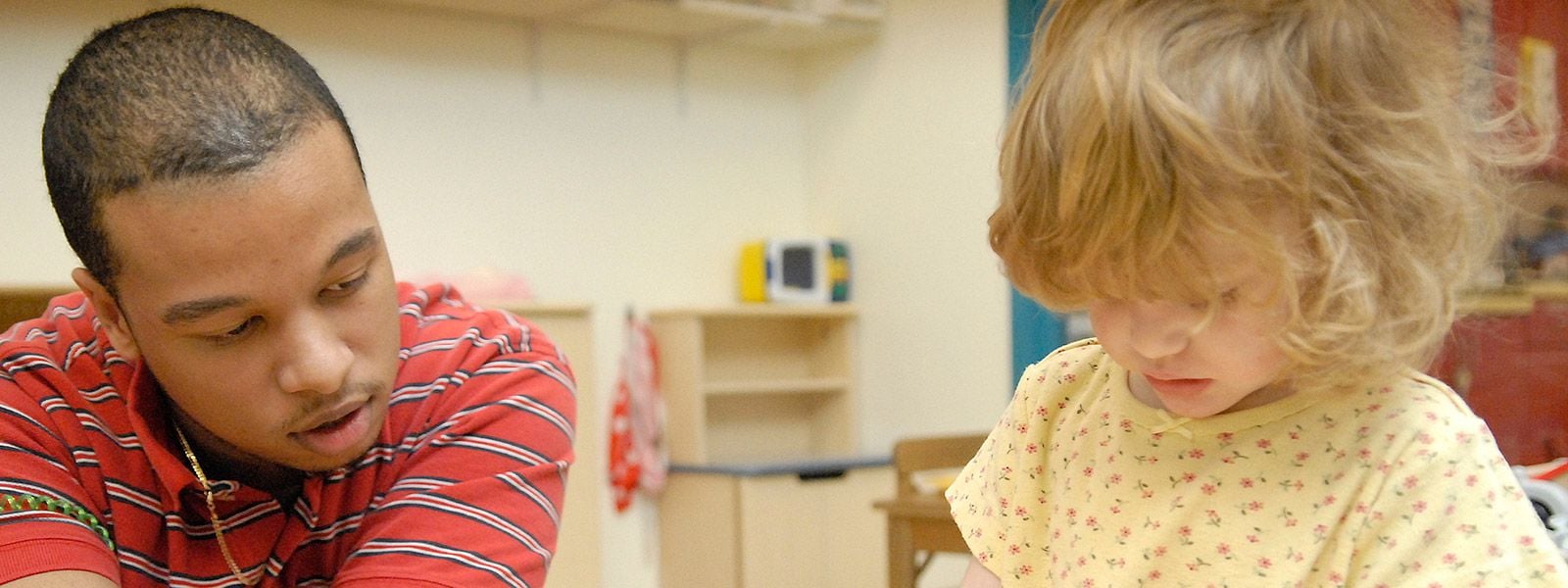 A childcare provider talks to a child in his care.