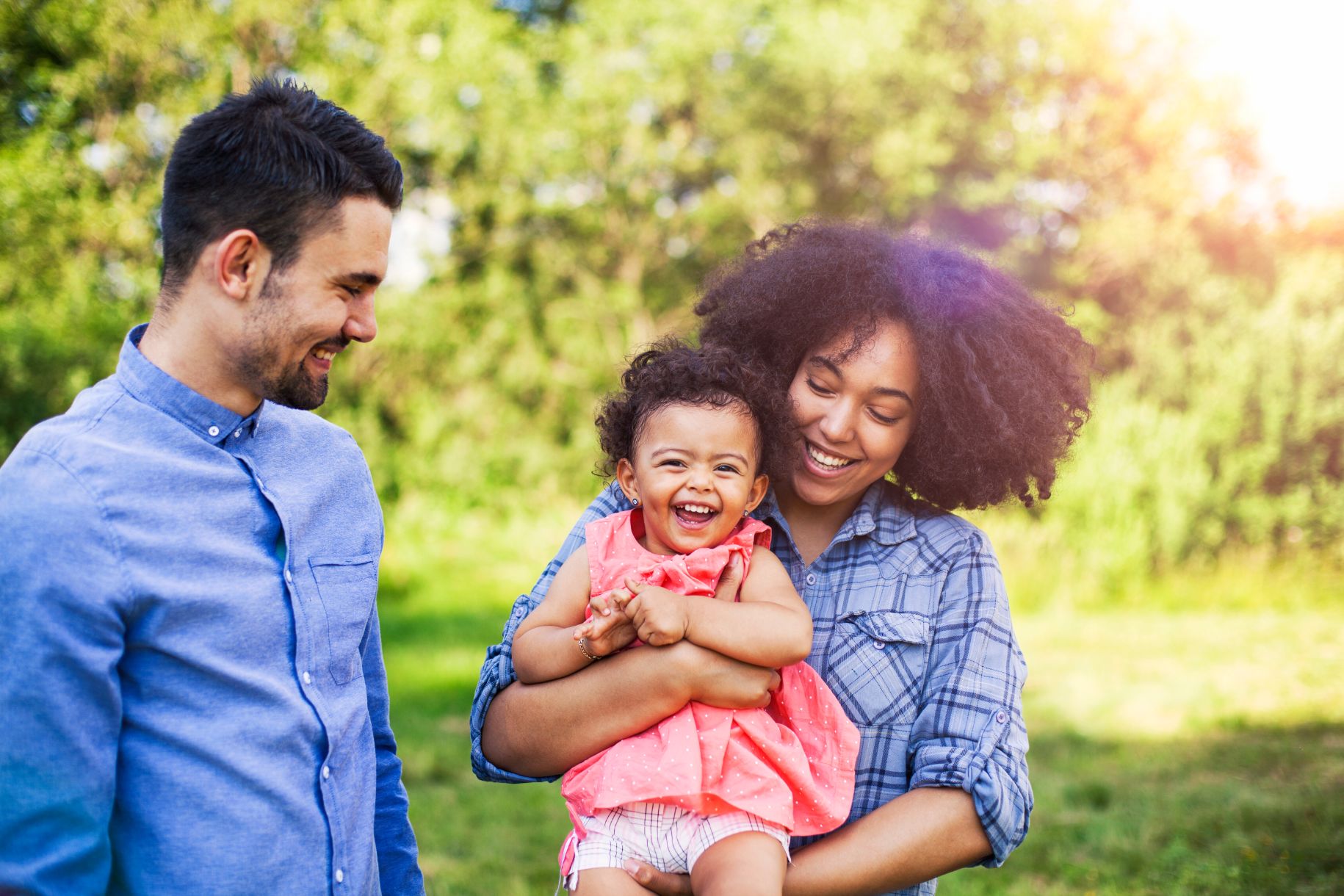 Family walking in field carrying young baby girl