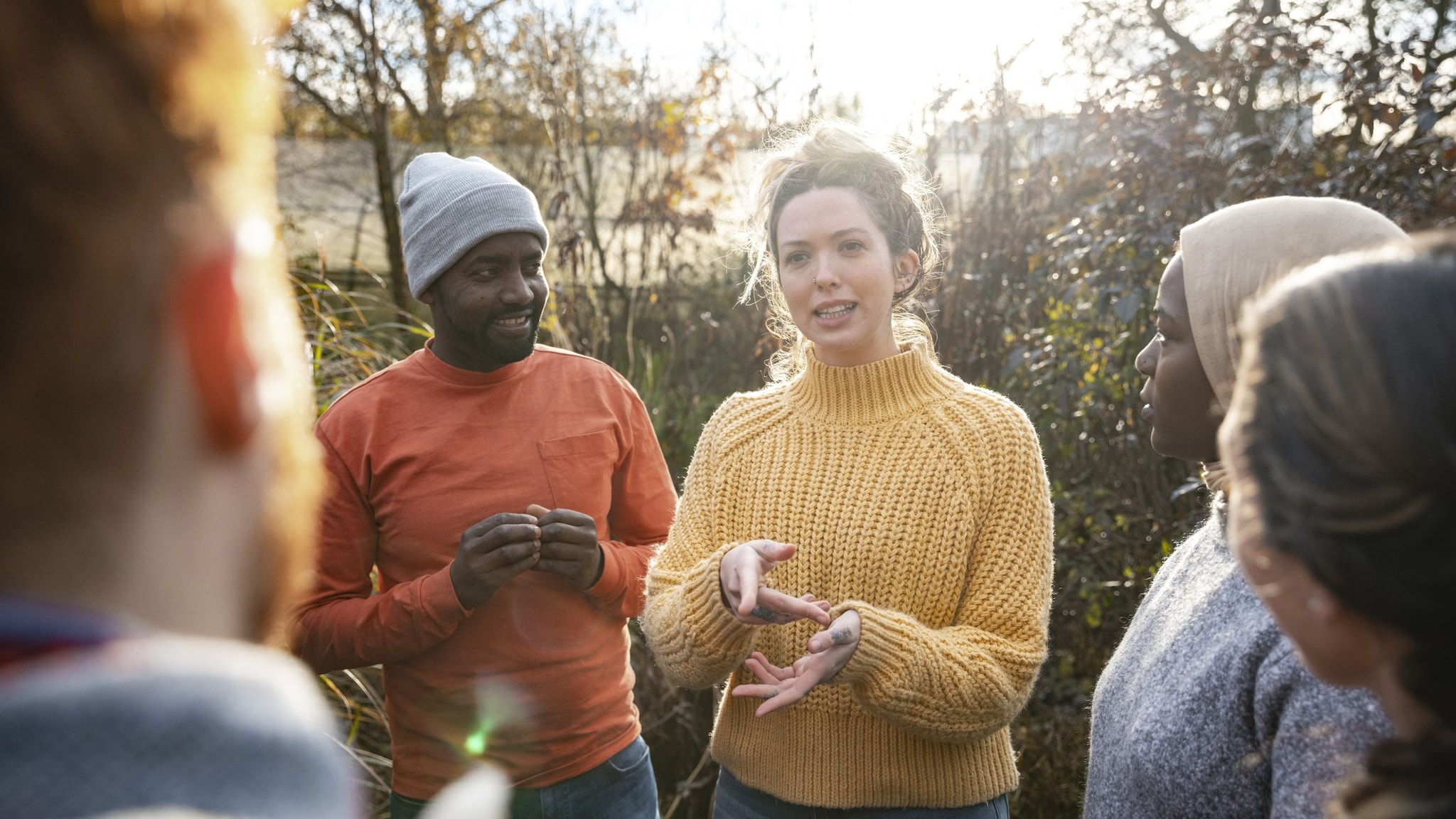 A woman talks to a diverse group of volunteers outdoors