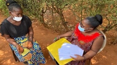 A woman administers a survey to a community member.