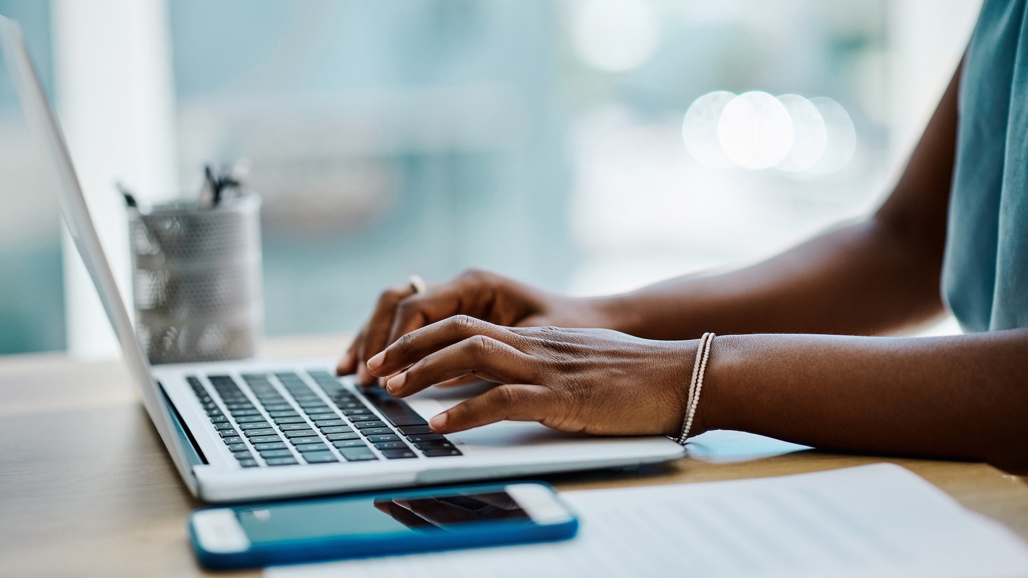 A woman's hands typing on a laptop