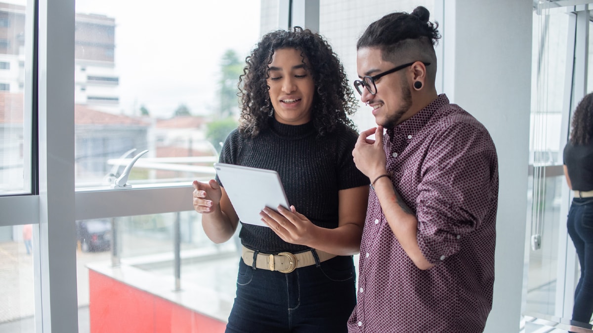 A black woman and transgender man review work in an office