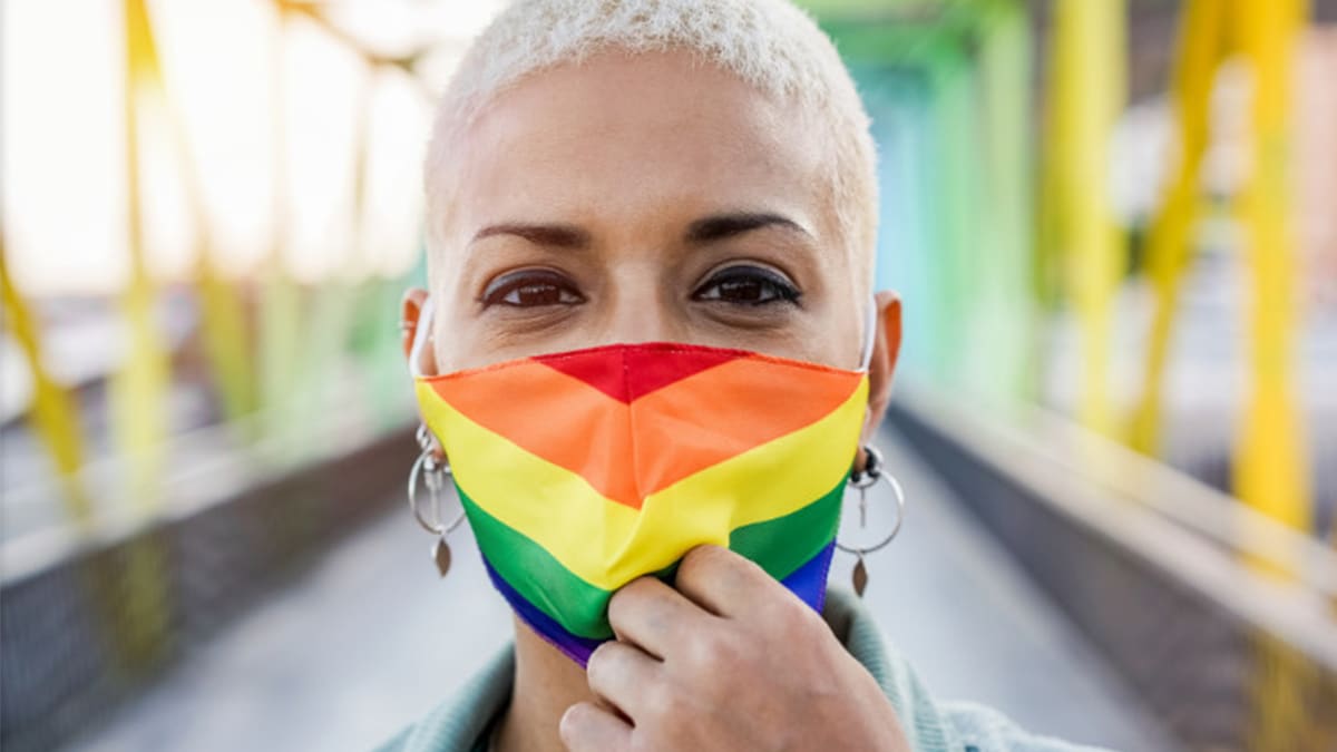 A person in a rainbow facial mask in an outdoor setting.