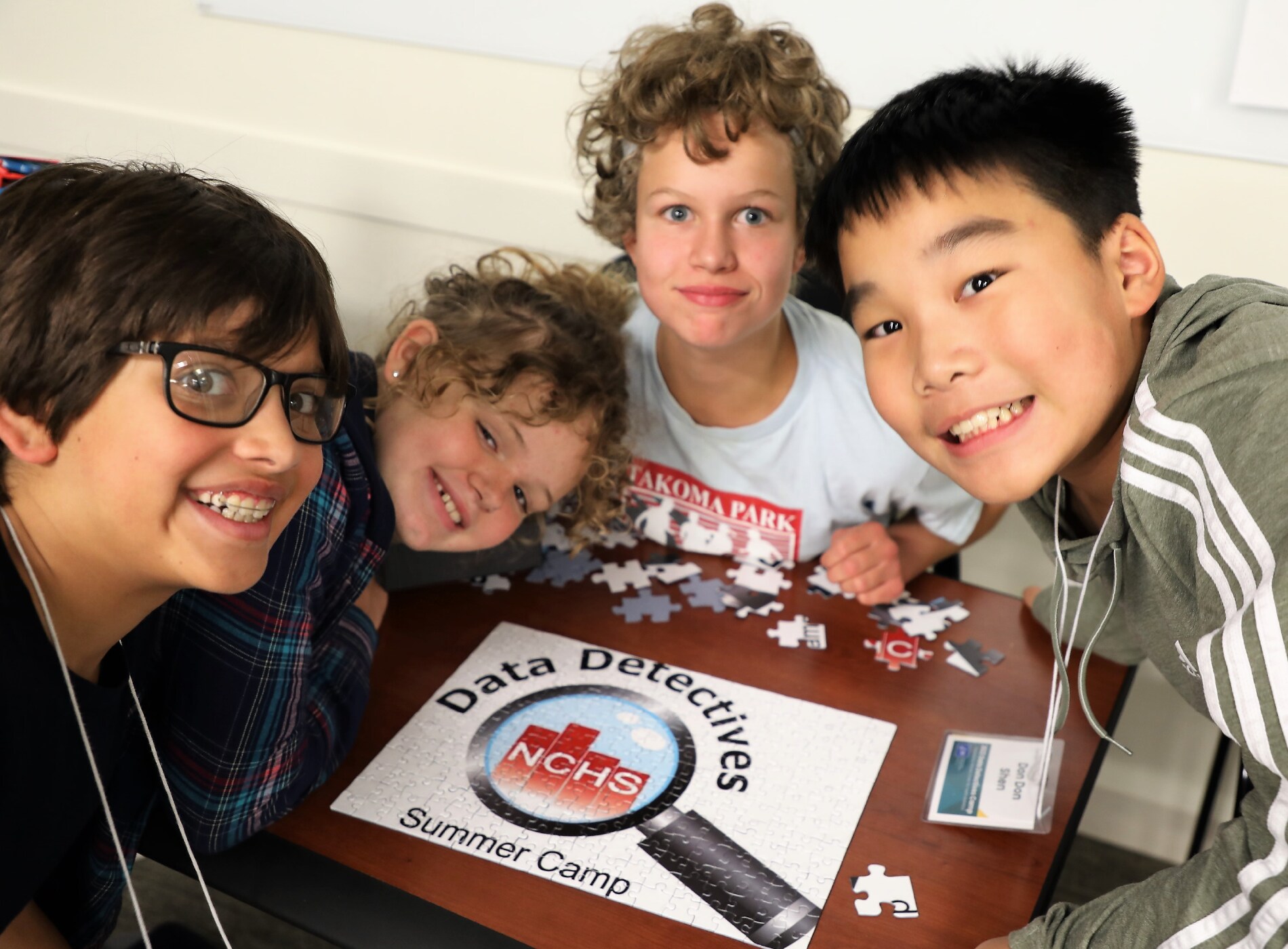 Portrait of 4 campers around a Data Detectives Camp puzzle