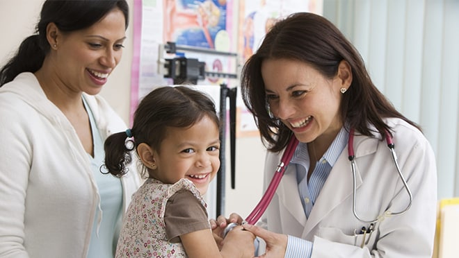 Pediatrician examines young girl as mother watches