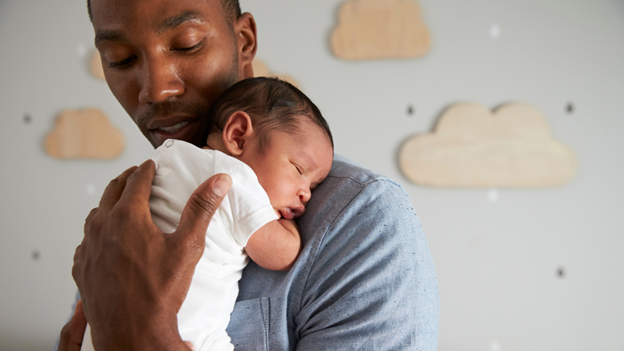 A parent holding their infant against their chest.