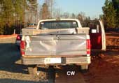 tailgate of the truck shows damage that resulted when the grader struck the truck.