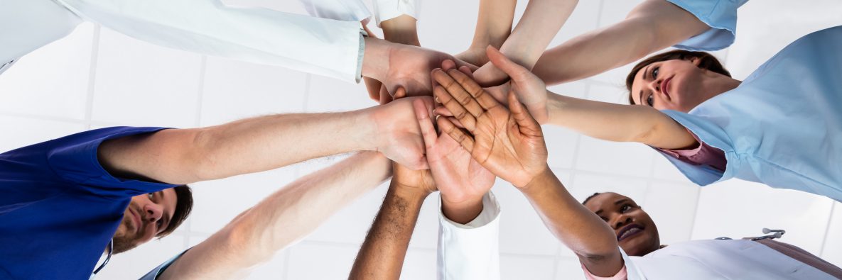 Directly Below Shot Of Doctor Stacking Hands Together