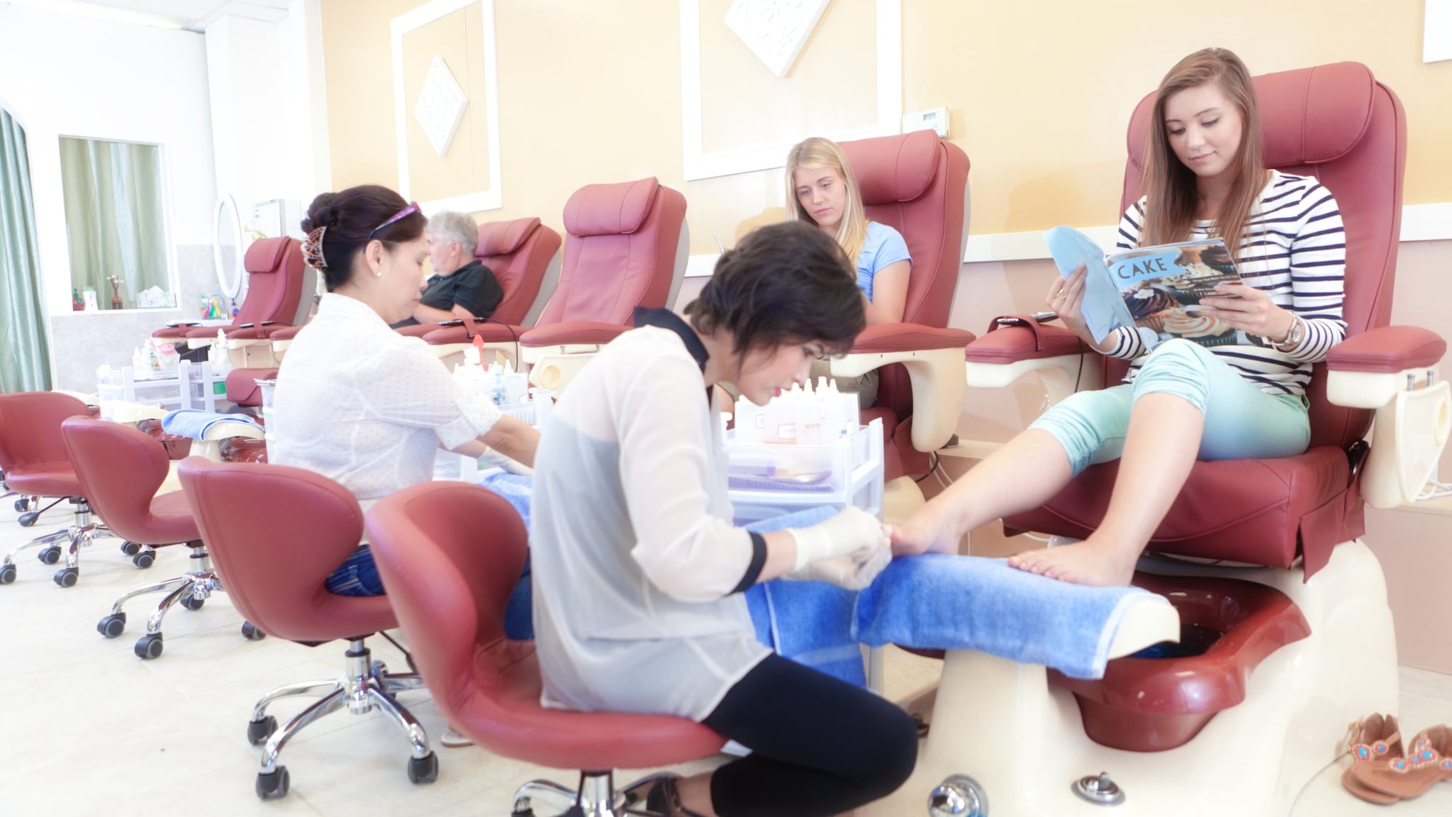 Two Asian nail technicians performing pedicures