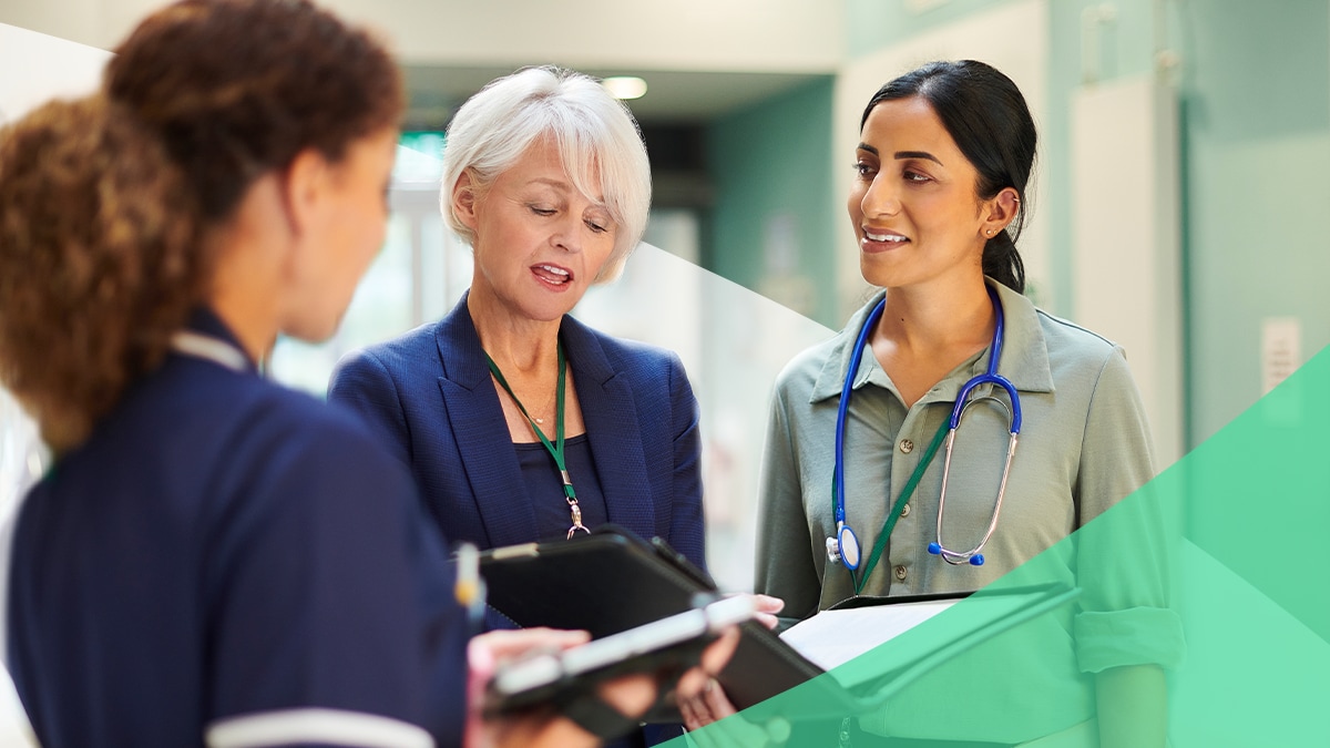 Doctor and executive have a conversation in a hallway. Both have relaxed body language.