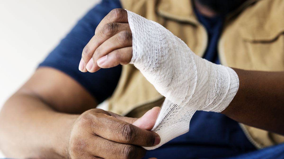 Photo of a mine worker bandaging hand.