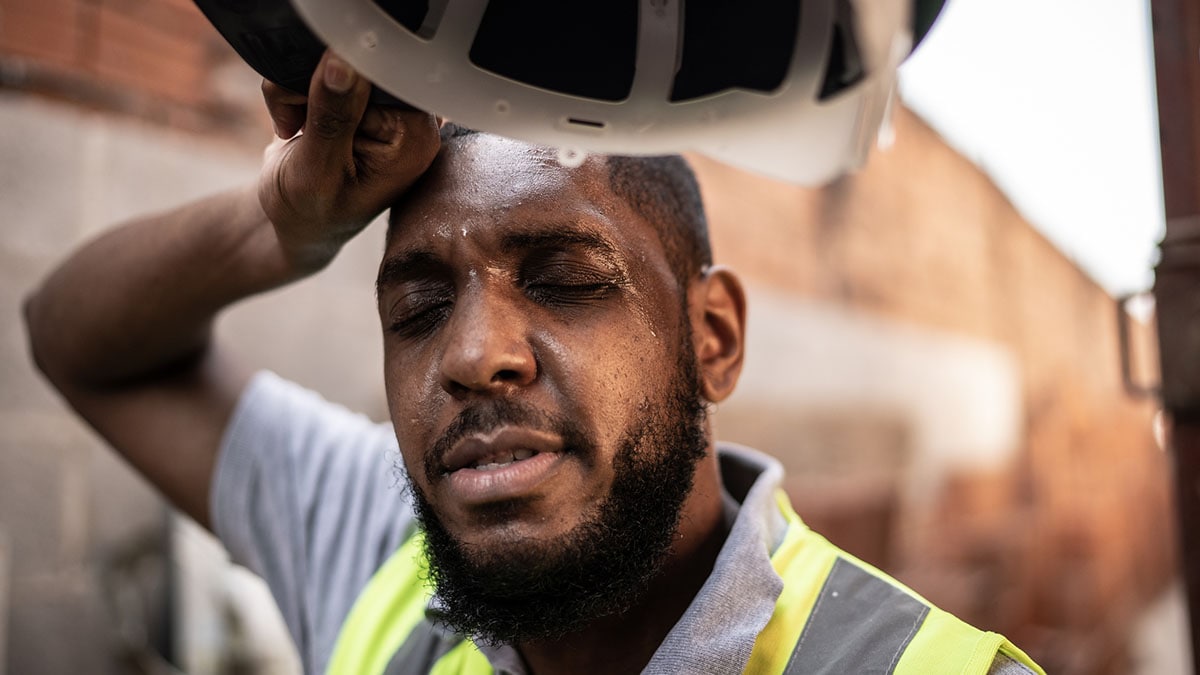 African American male construction worker sweating while taking a rest break on a construction site.