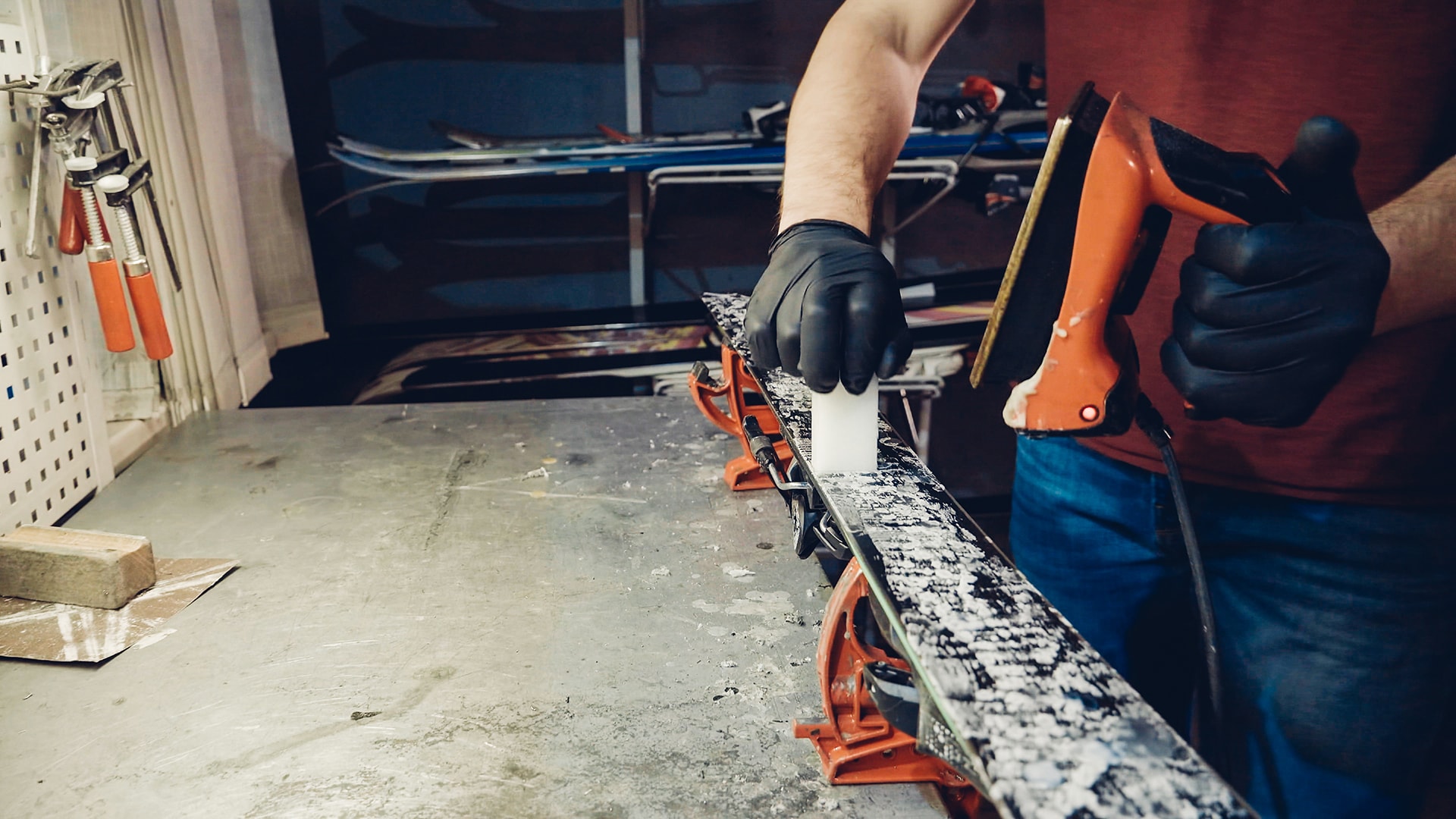 A worker waxing a ski on a bench.