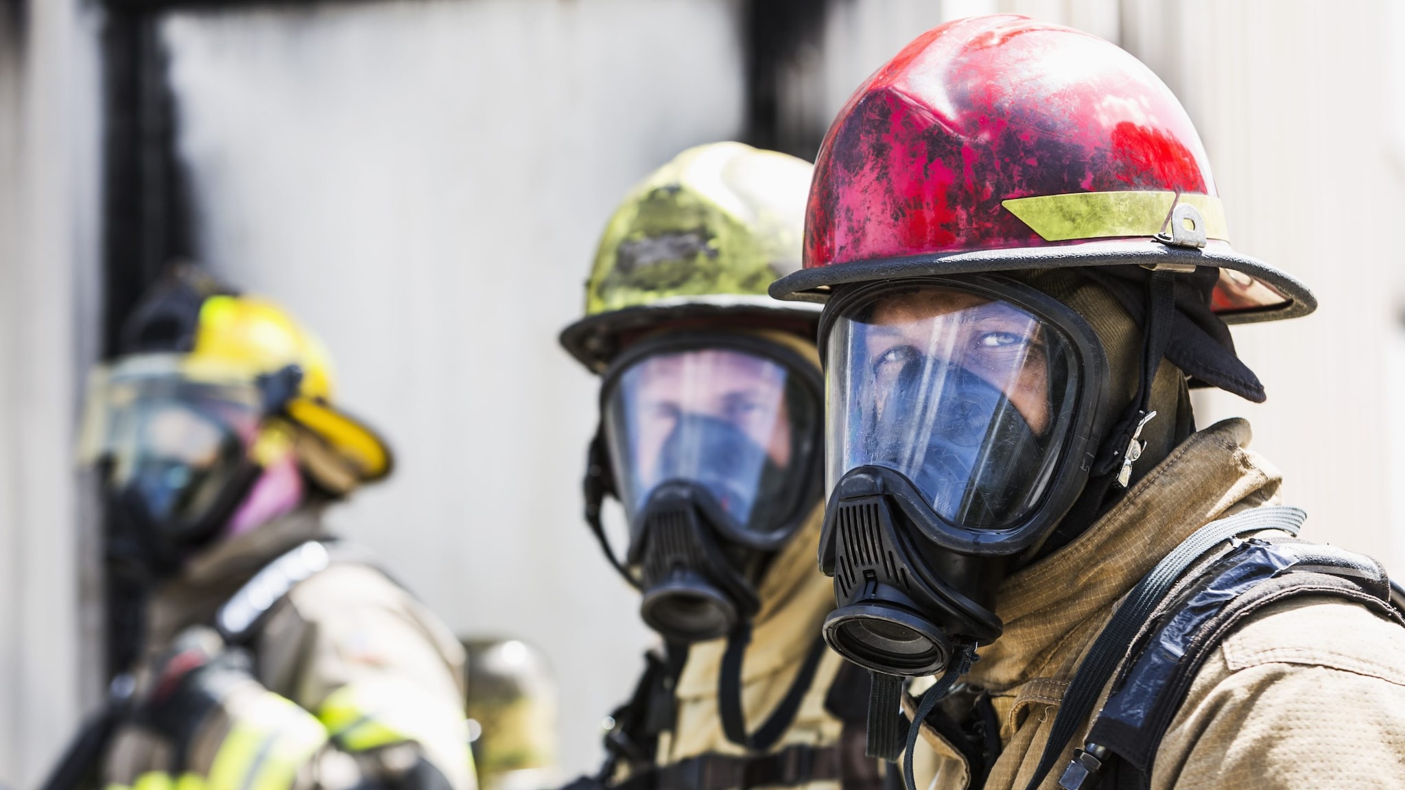 Three firefighters wearing personal protective equipment. Front two firefighters are looking into camera.