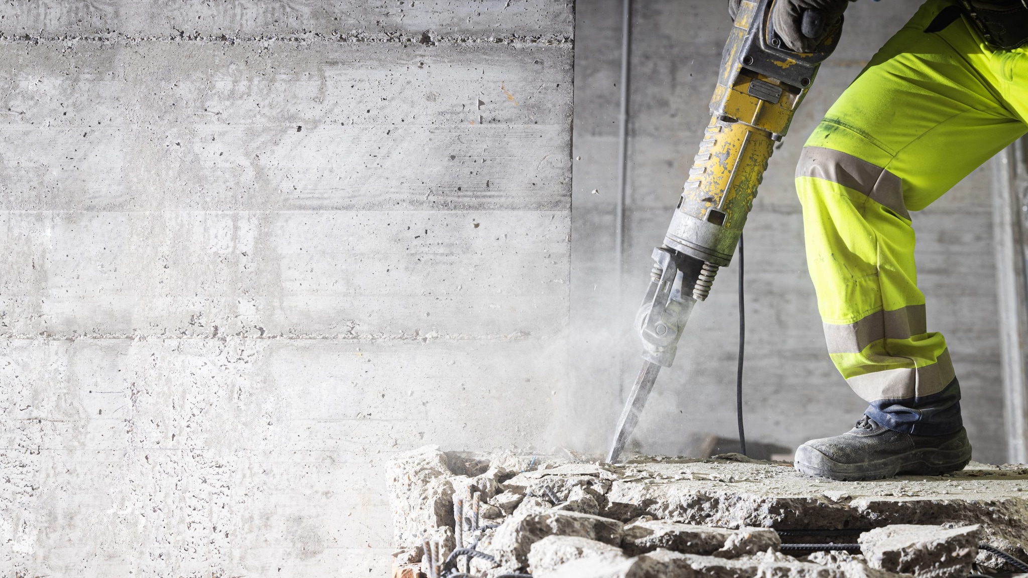 Person operating a jackhammer, breaking up concrete.