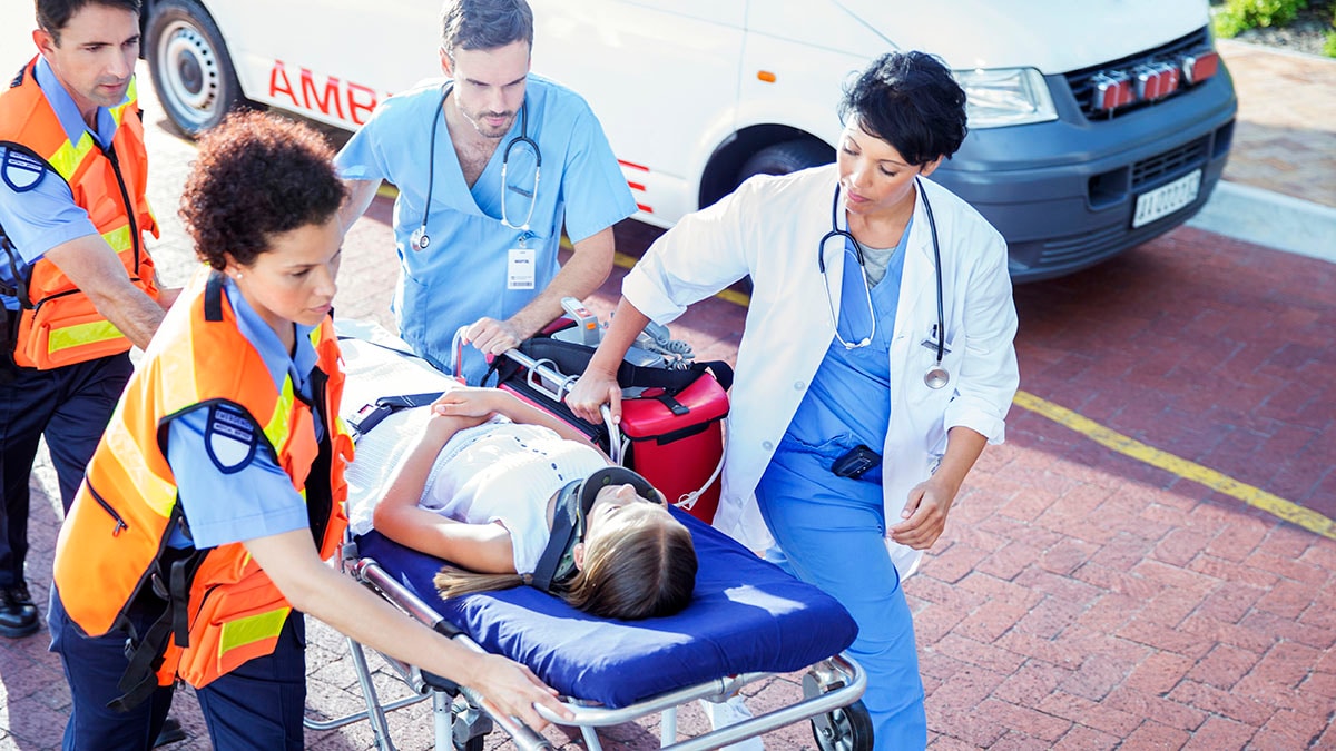 Doctor, nurse and paramedics wheeling patient on stretcher