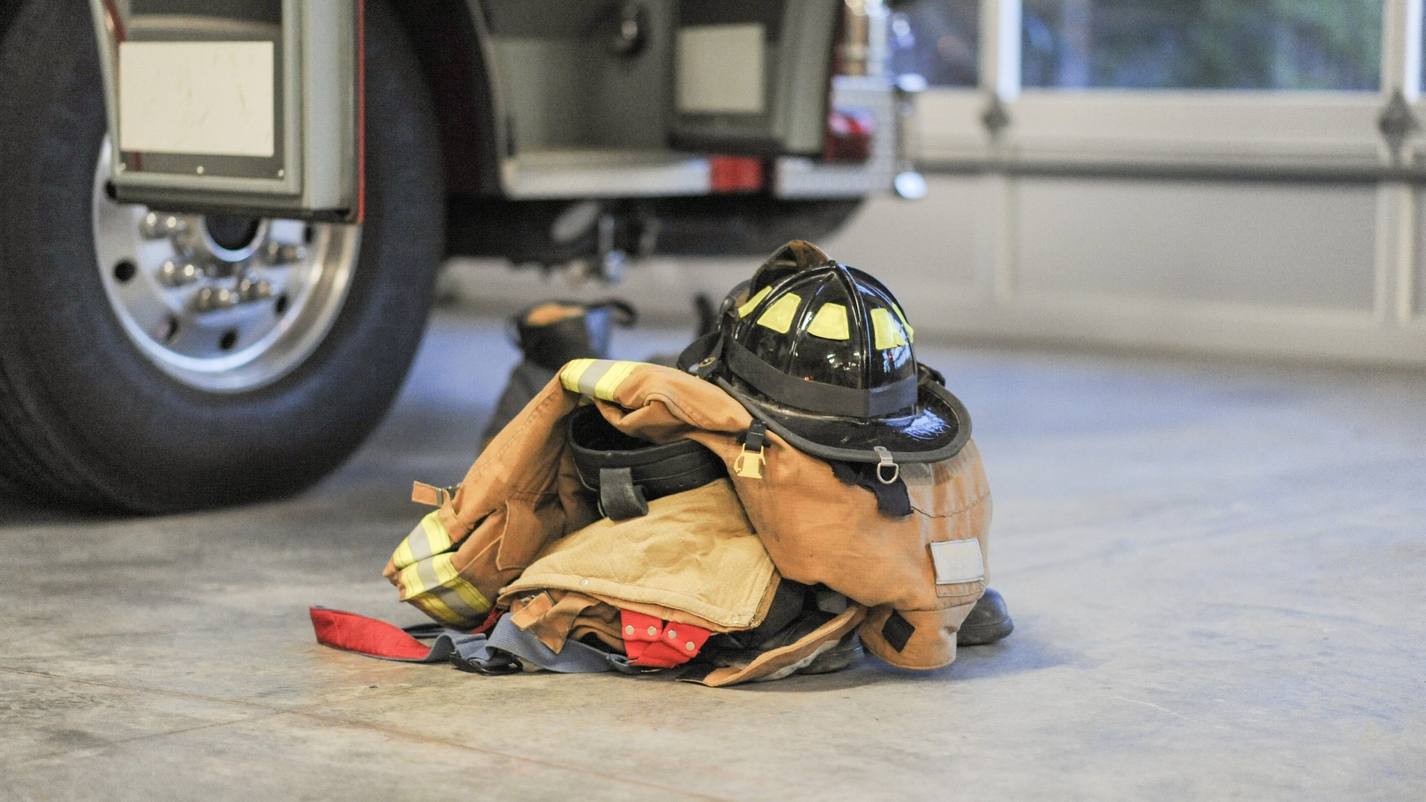 A stack of firefighter gear is next to a firetruck.